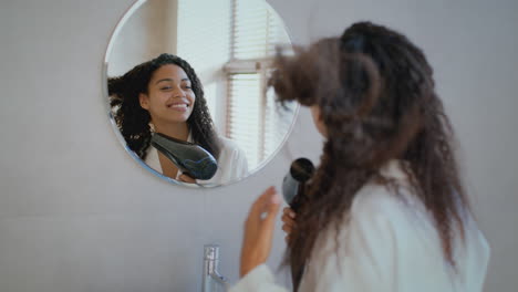 woman styling her curly hair in a bathroom