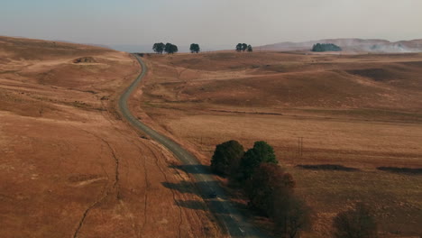 drone shot of a vintage black austin westminster car driving through the hills of south africa during dry winter conditions