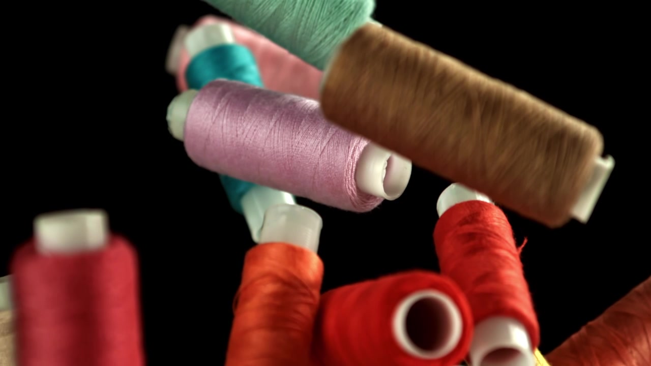 Colorful Spools of Sewing Thread Falling in Slow Motion