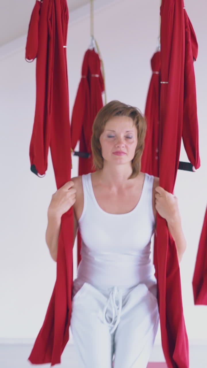 happy women laugh smile and enjoy swinging on bright aerial fly yoga hammocks in modern pilates room