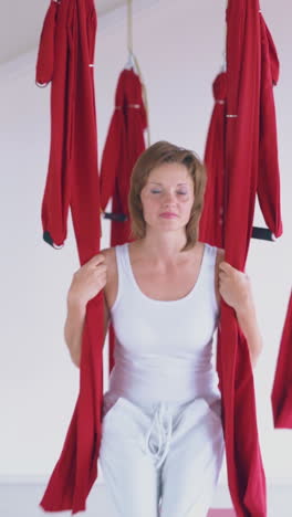 happy women laugh smile and enjoy swinging on bright aerial fly yoga hammocks in modern pilates room