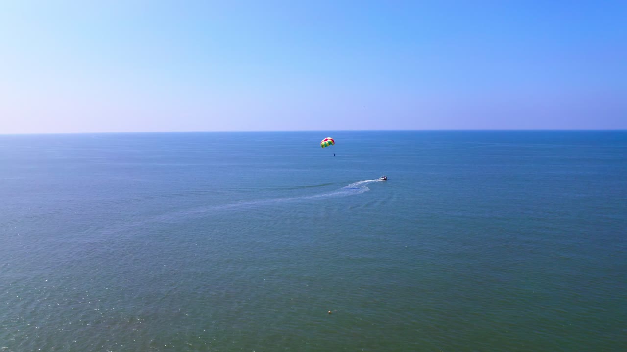 parasailing with boat in Arabian Sea at colva beach. day time, push in shot, drone shot, 4k