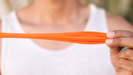 person stretching a bright orange balloon, close-up view