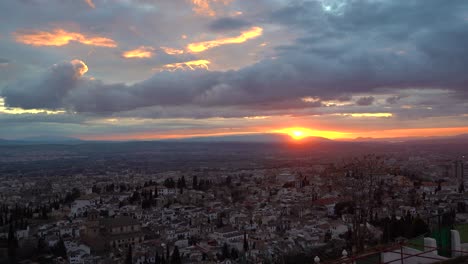 Sonne,-Die-Langsam-Hinter-Den-Bergen-Untergeht,-Während-Des-Pulsierenden-Sonnenaufgangs-Mit-Stadtbild