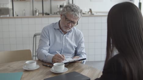 Expert-and-male-customer-meeting-and-signing-agreement