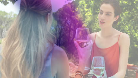 two women holding wine glasses in garden, with animated business growth graph rising above table