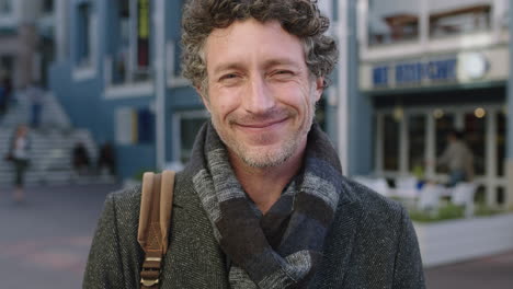 slow motion portrait of attractive mature caucasian man smiling confident at camera wearing scarf in urban background