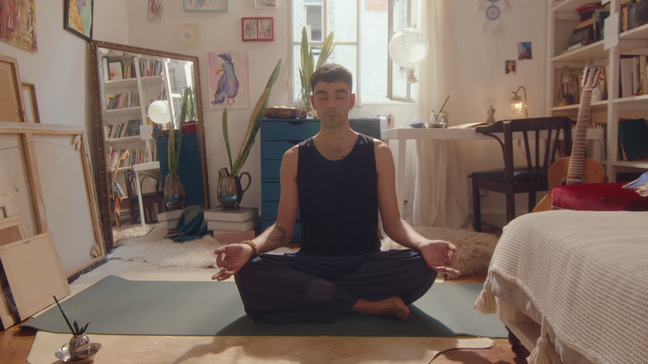 Giovane uomo che medita a casa durante la pratica yoga