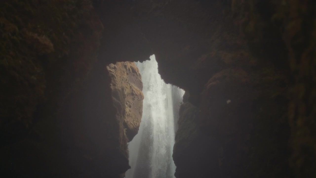 Maestosa cascata vista attraverso l'apertura di una grotta rocciosa