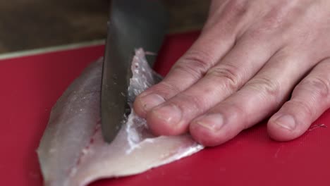 el chef elimina hábilmente los huesos de las costillas del jurel japonés con un cuchillo afilado