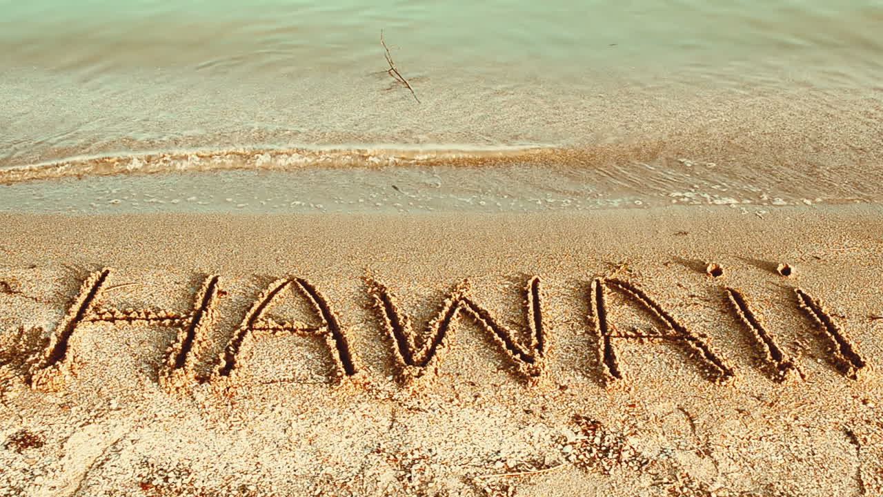 Inscrição 'Hawaii' feita em uma bela praia. Inscrição na areia, a praia