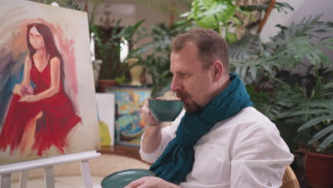 artist takes break to drink hot beverage. painter mental break and assessment of evolving masterpiece in art studio with cup of strong coffee