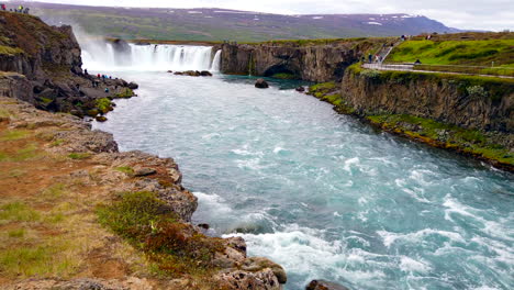 Wunderschöner,-Mächtiger-Godafoss-Wasserfall,-Island-Pfanne-–-Dolly-Aus-Felsen-–-Bach-Zu-Breiten-Wasserfällen-Mit-Touristen-In-Der-Ferne,-4-Km-Prorezhq,-Am-Fluss-Skjálfandafljót-Im-Norden-Islands-In-Der-Nähe-Von-Akureyri