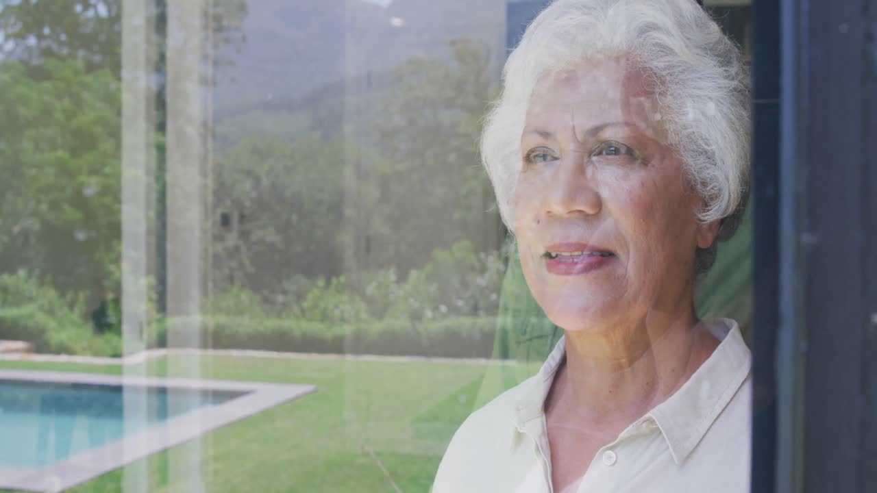 Senior African American husband and mixed race woman looking at their window, reflection of the wind