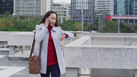 asian woman walking talking on smartphone and using smartwatch