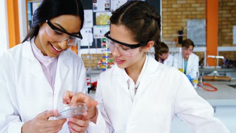 escolares sonrientes experimentando en una pieza de vidrio en el laboratorio