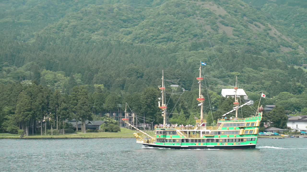 녹색 배는 나무와 산이 있는 해안선을 따라 항해합니다.