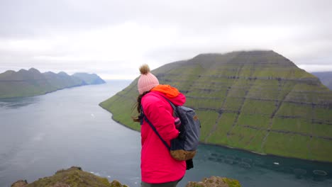 mujer en la cima de la montaña klakkur agarrando un frasco de su mochila después de una caminata