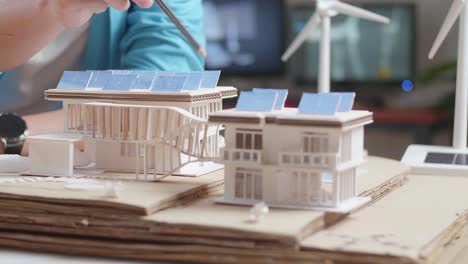 cerca de dos colegas ayudándose unos a otros a construir el modelo de una pequeña casa con panel solar