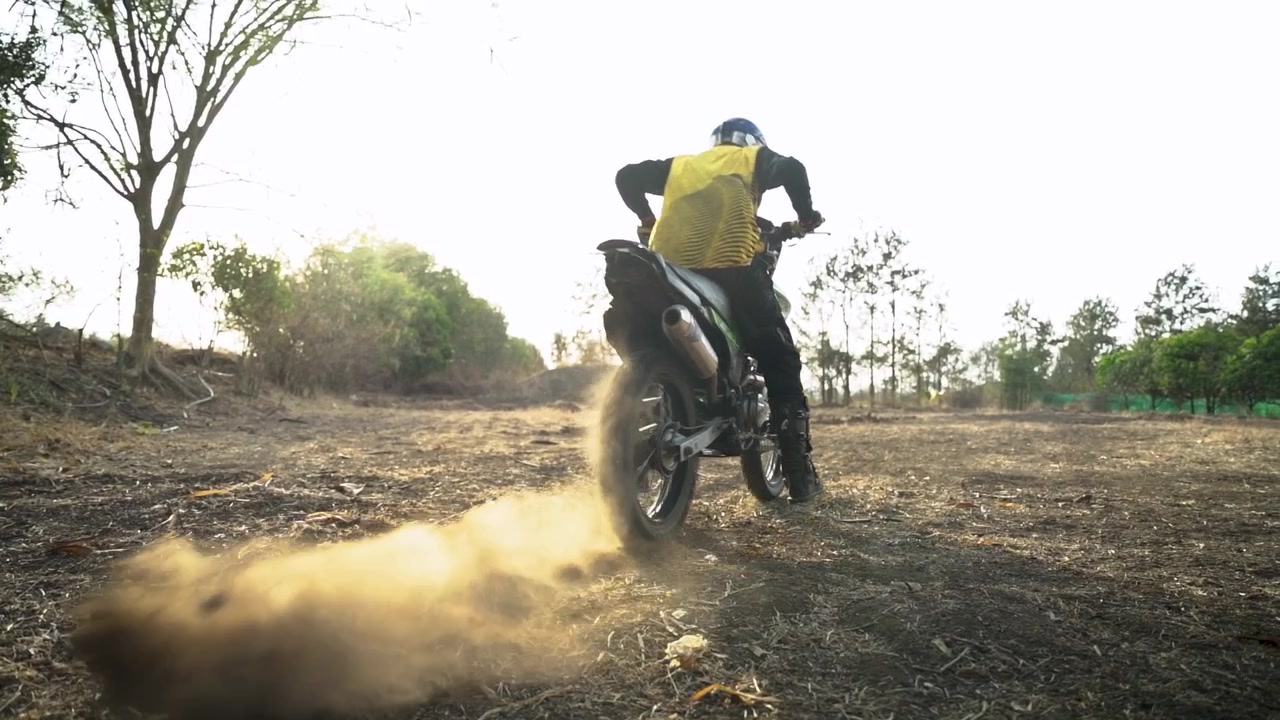Piloto de motocross pilotando uma moto de trilha e levantando poeira em uma pista de terra
