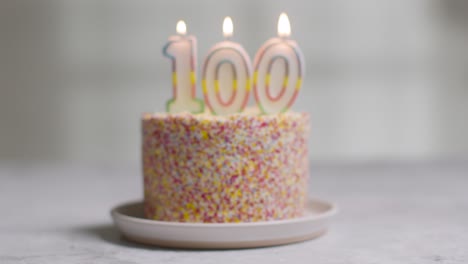 studio shot birthday cake covered with decorations and candle celebrating one hundredth birthday being blown out