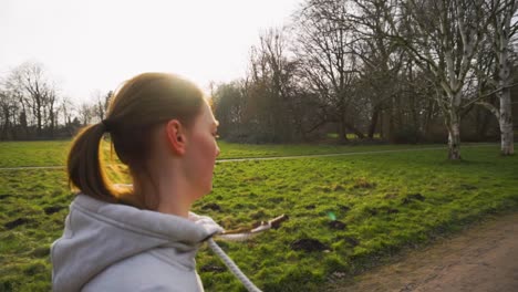 a woman walking through a park on a sunny day.