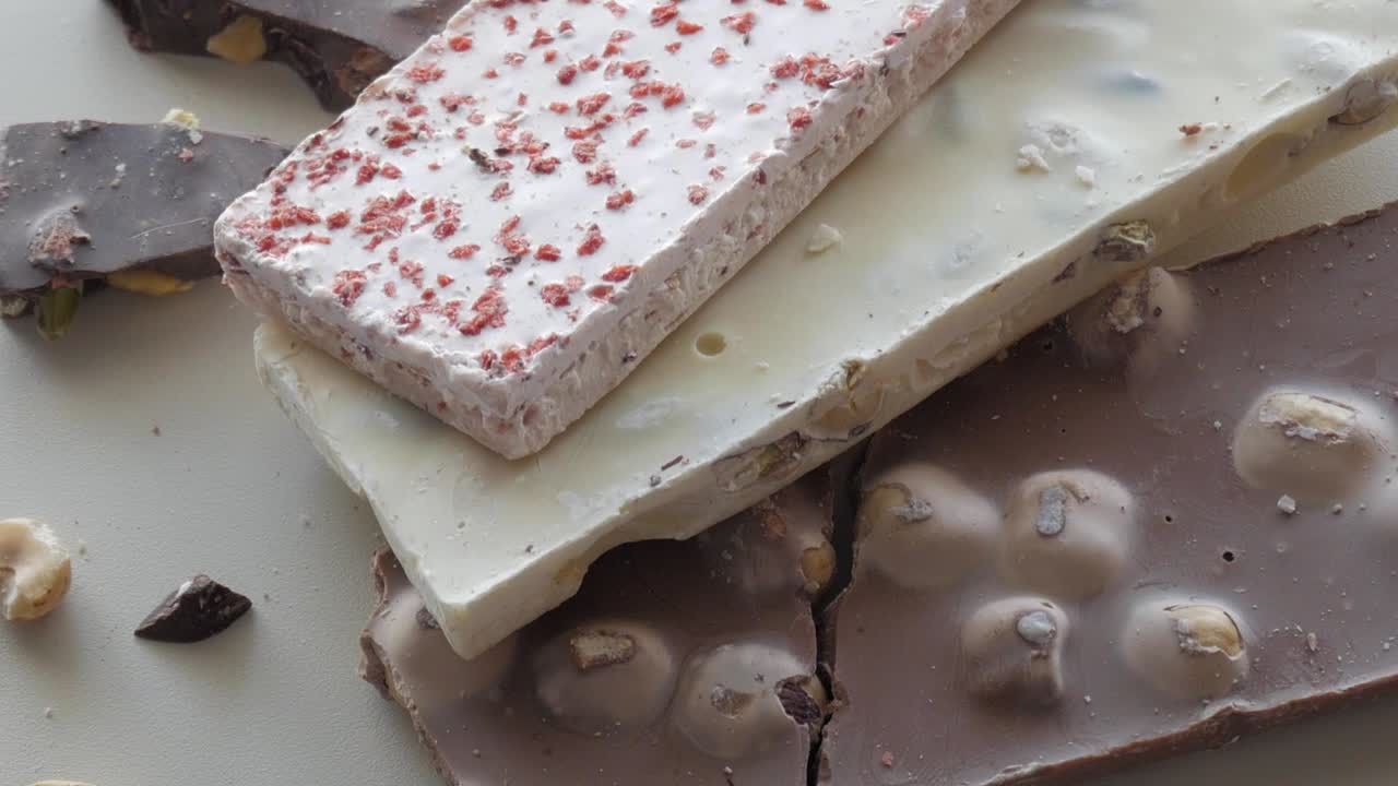Dark and white chocolate assortment with nut garnishes on a bright white background, creating an enticing visual presentation.