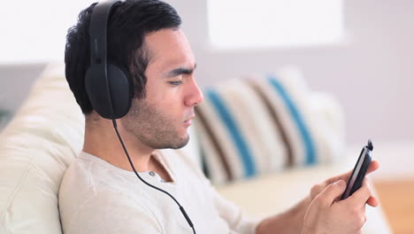 Un-Hombre-Guapo-Con-Auriculares-Escuchando-Música-En-Su-Teléfono-Inteligente.