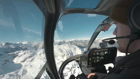 photographer in the front seat of a helicopter ride, flying through the snowy mountains of canada, bc