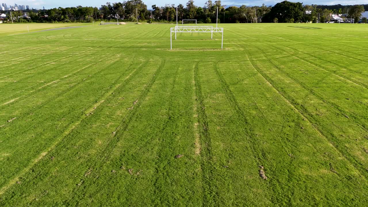 Aerial view of a soccer field in Gold Coast, Australia. The drone captures the field's green expanse and goalposts under clear skies