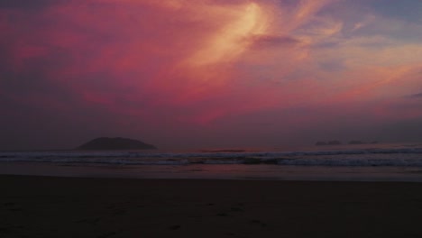 dramática puesta de sol rosada sobre una playa tranquila y una isla lejana