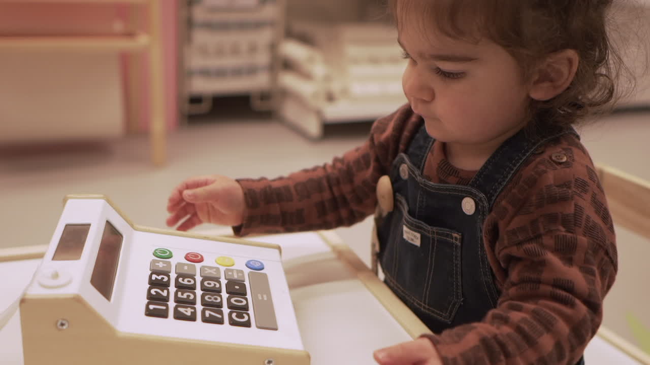 niño jugando al juguete de la caja registradora mientras está sentado dentro de la tienda ikea
