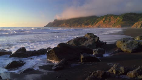 usal beach campground golden sunset pacific ocean waves crashing rock boulders black sand california mist fog bluffs rugged lost coast remote untouched sinkhole wilderness nature landscape static shot