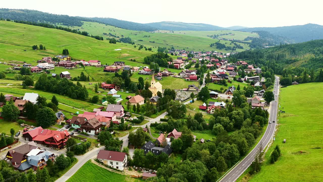 Drone footage of Osturňa village in northern Slovakia, showcasing traditional houses, green meadows, and rolling hills in summer. Peaceful rural life in the heart of nature. (4K)