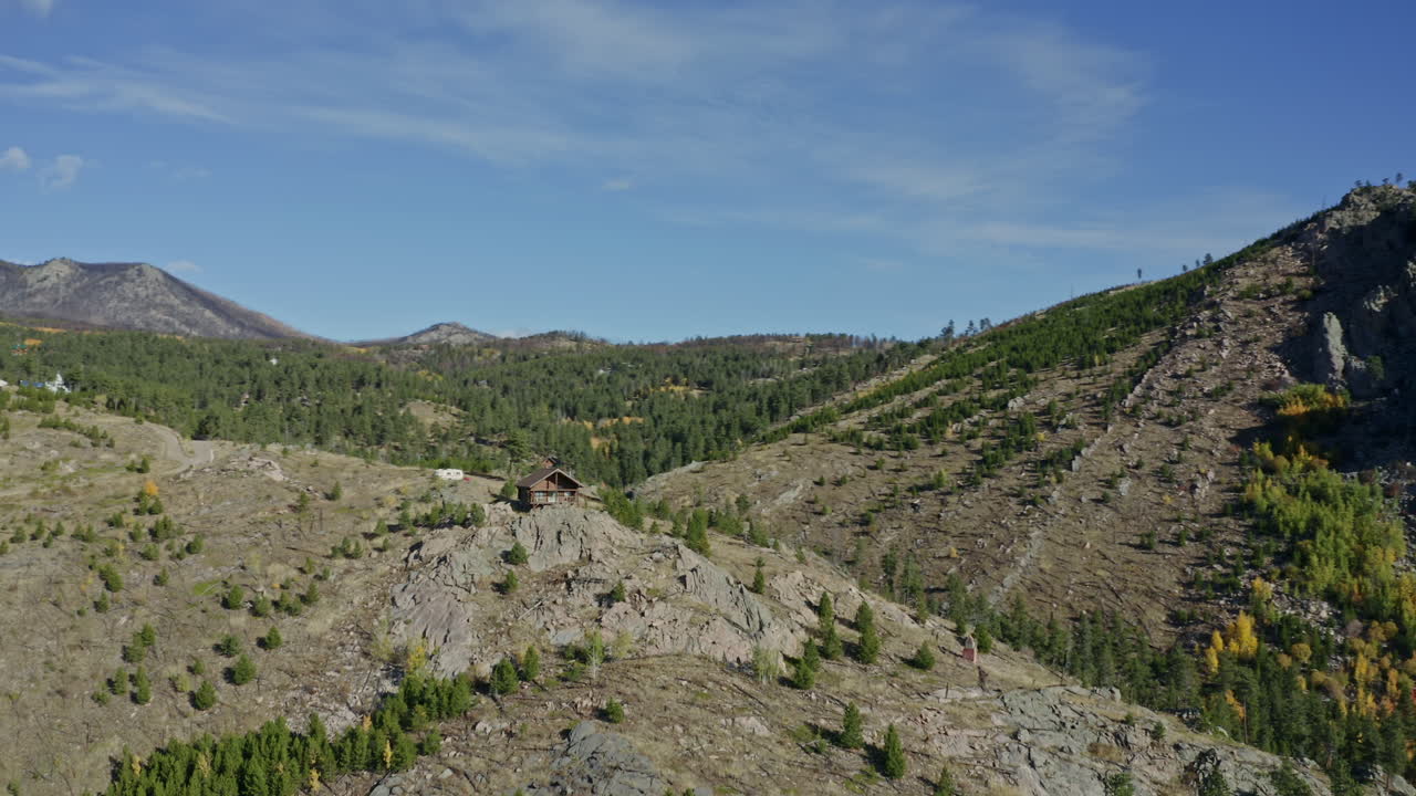 pequeña cabaña aislada en órbita aérea en la ladera de la montaña en las montañas rocosas durante el otoño, 4k