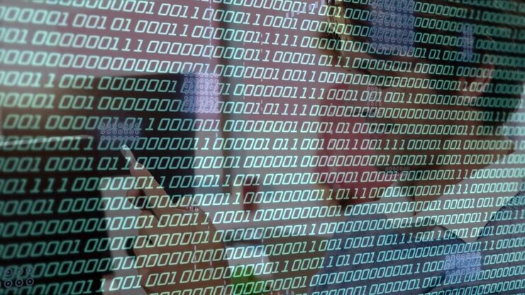 Woman leaning to screen, faint binary overlay moving icons, revealing necklace, reading tech code