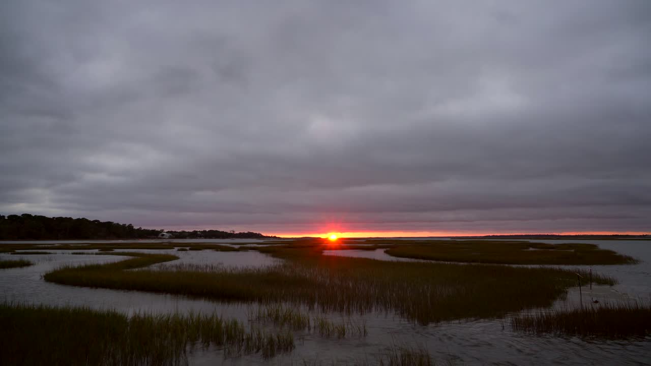 Crystal Coast Sunset Peeking Through the Clouds Over a Flooded Marsh in Emerald Isle - Fixed Cold Shot of the Delta with Running Water