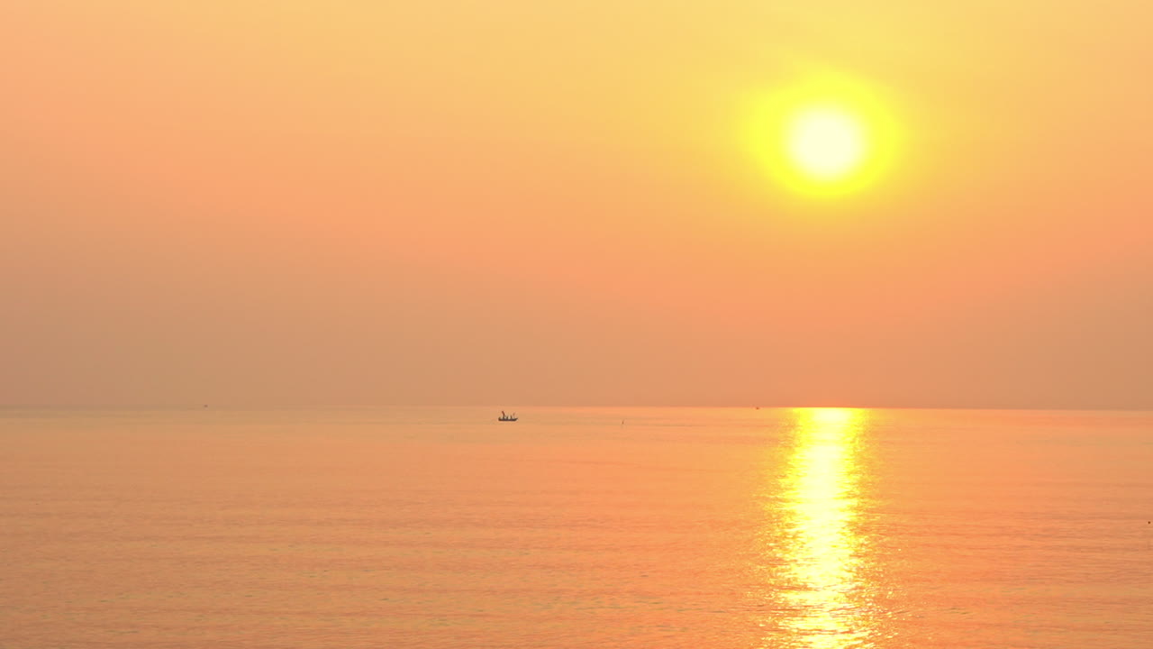 오렌지색, 분홍색, 노란색 일몰의 바다에 작은 배가 떠 있다