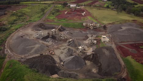 orbit shot of open stone quarry, piles and excavators working around near iguazu river, brazil