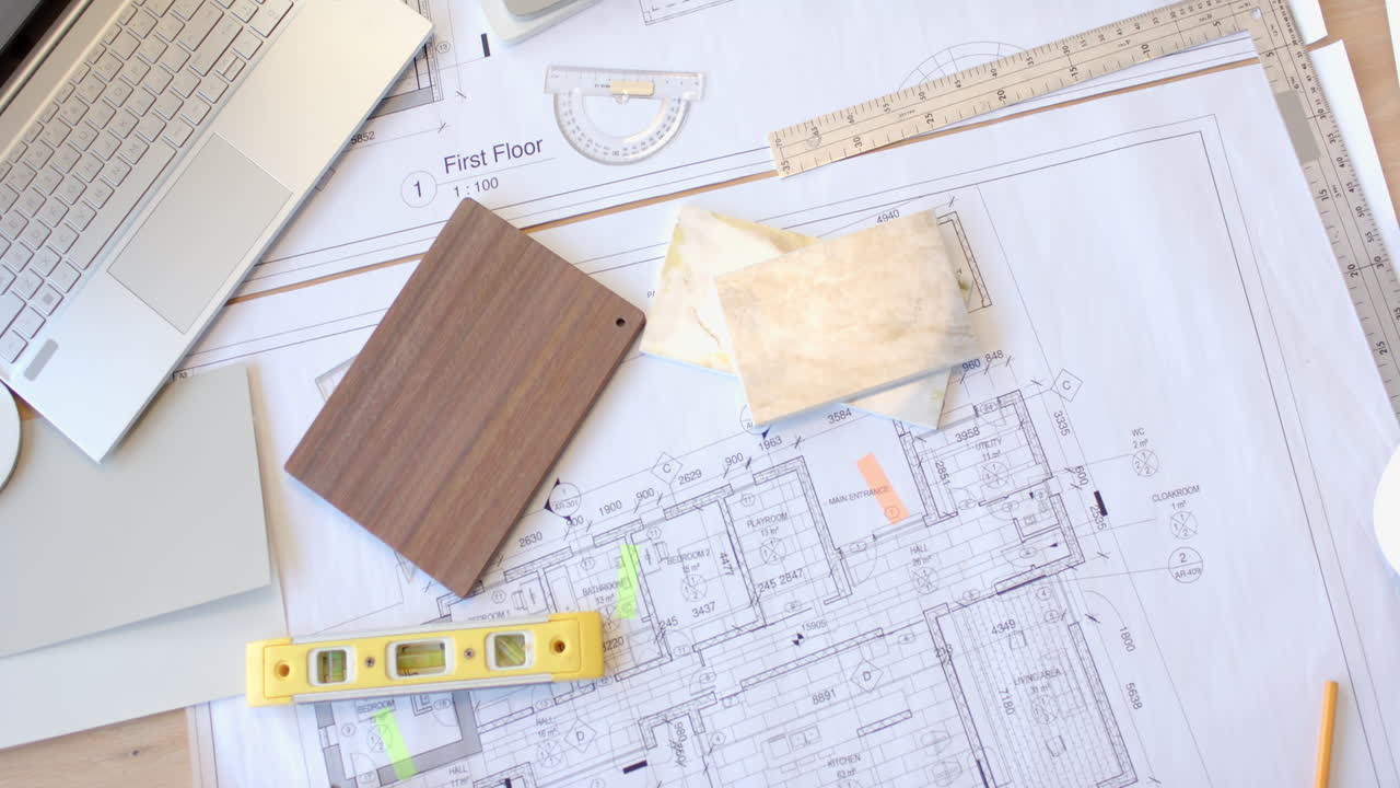Planning construction, architectural blueprints with level, ruler, and wood sample on desk