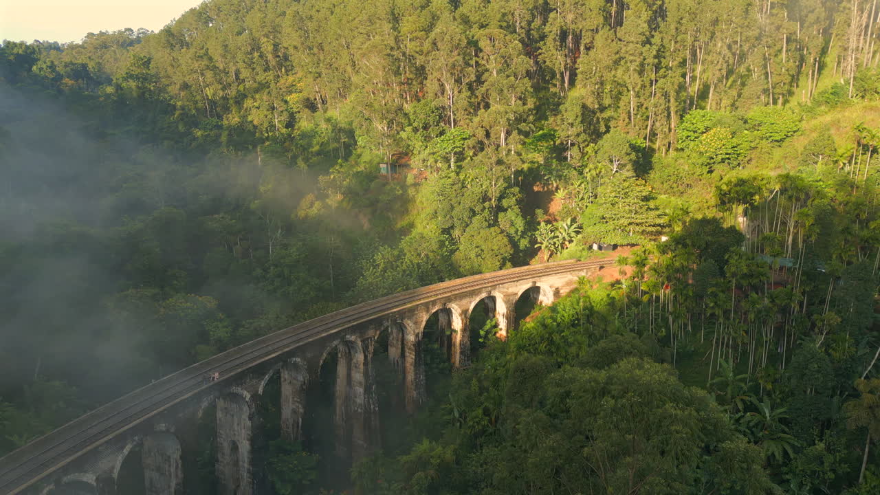Toma aérea de establecimiento con dron del Puente de los Nueve Arcos en una mañana soleada y brumosa en Ella, Sri Lanka