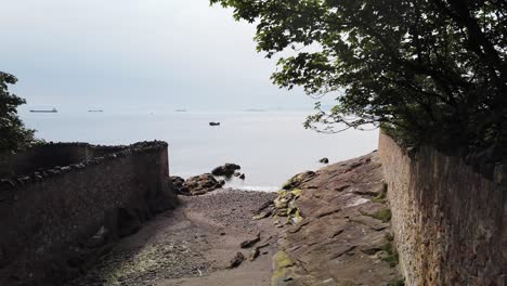 Small-fishing-boat-passing-near-the-shore-in-between-two-walls-on-the-Firth-of-Forth-Fife-Scotland