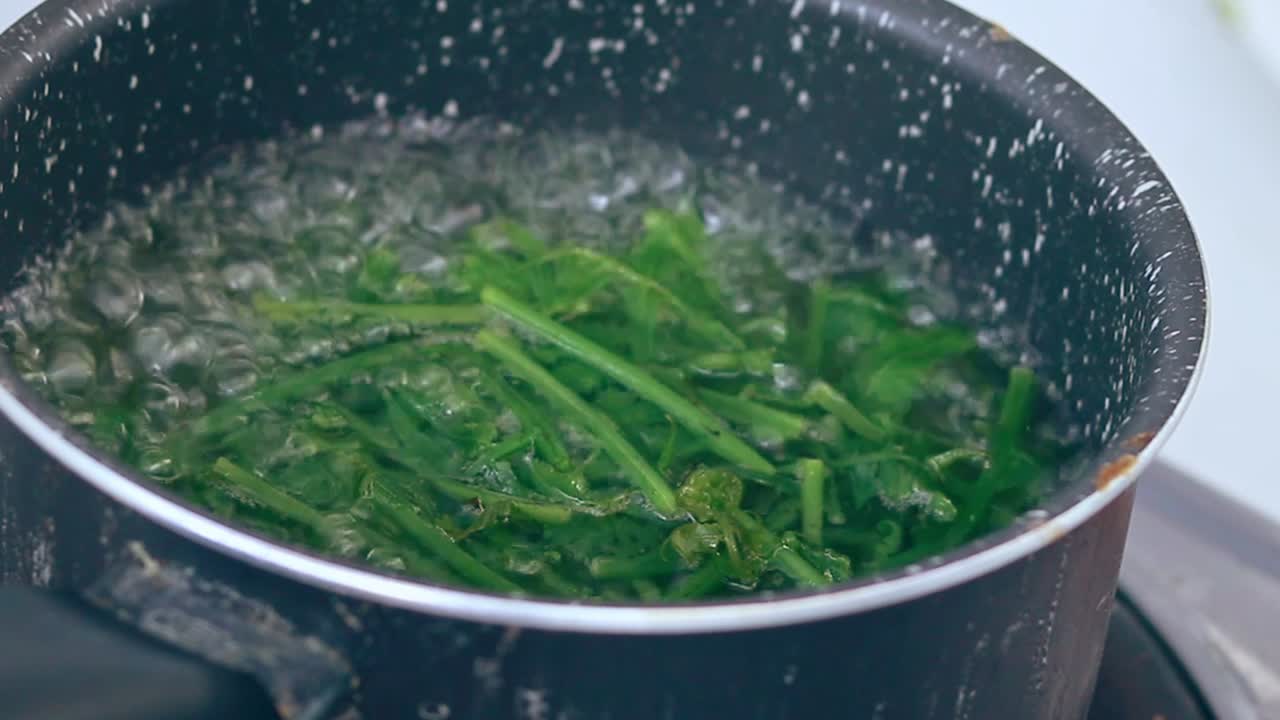 Ambient motion of wild edible fiddlehead ferns or Diplazium esculentum blanching in boiling water to make pako salad, an authentic Filipino local delicacy