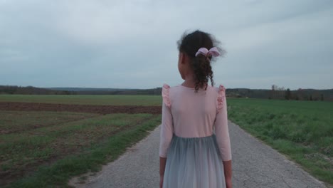 little girl walking alone in thought on empty field road at sunset in schonaich germany