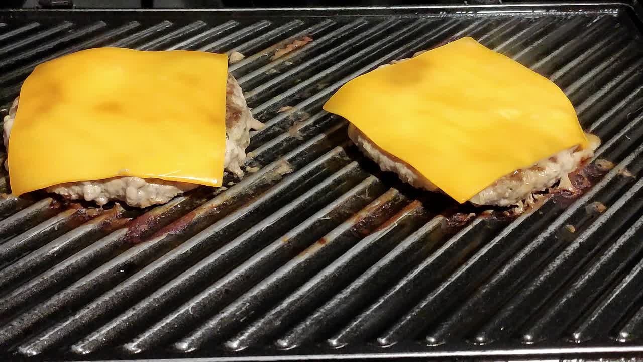dos hamburguesas con queso caseras cocinadas en una parrilla negra