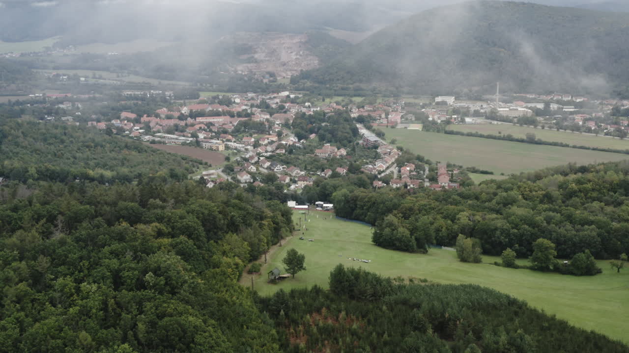 Vista aérea de pessoas em uma pista de esqui acima de uma cidade rural na República Tcheca em um dia de neblina.