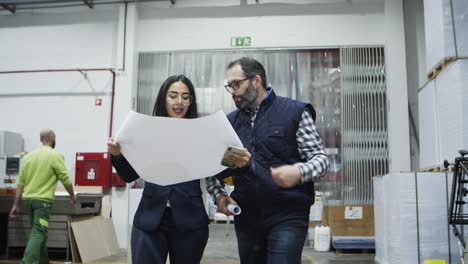 serious factory workers walking at printing house with blueprint