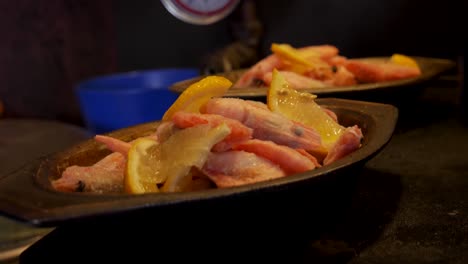 handheld close up shot of frozen shrimps in a dirty silver bucket with lemons in a slightly dirty countryside kitchen