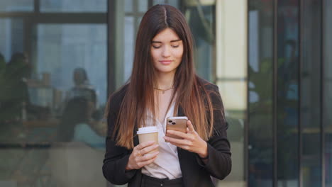 una joven banquera sonriente usando un teléfono afuera