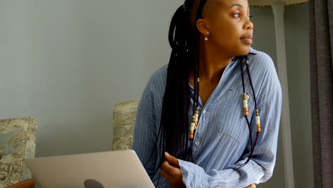 Side-view-of-young-black-woman-using-digital-tablet-and-sitting-on-the-couch-in-comfortable-home-4k